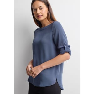 A women's boatneck top in a soft blue shade with rolled sleeves and a slight high-low hem. Features a logo.