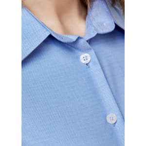 A close-up of a light blue button-up shirt featuring a collar and two buttons. The shirt has a logo.