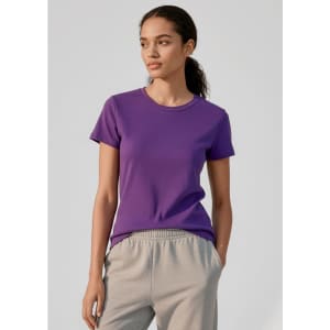 A purple women's short sleeve tee displayed on a model, paired with grey pants. The tee features a simple design and branding.
