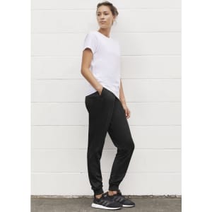 Track pants in black, styled with a white t-shirt and black sneakers. The pants feature pockets and a relaxed fit.