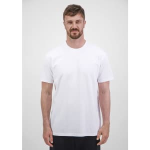 A man wearing a plain white short sleeve tee, standing against a neutral background. The tee features a logo.
