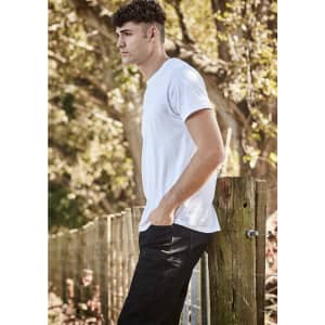A white men's t-shirt is displayed on a model standing beside a wooden fence in a natural outdoor setting.