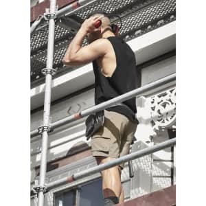 A sleeveless black tee worn by a man on scaffolding, paired with khaki shorts and work boots, during a construction task.