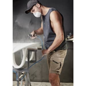 A sleeveless black tee worn by a man working on a surfboard in a workshop, wearing a mask and cap.