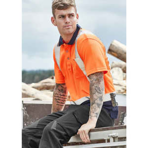 Hi-vis spliced short sleeve polo in bright orange with shoulder taping, featuring a model with tattoos seated outdoors.