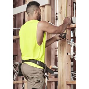 A man wearing a fluorescent yellow sleeveless tee is working with tools in a construction setting.