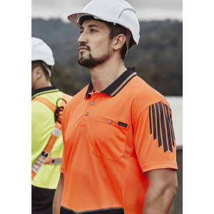A man wearing an orange hi-vis short sleeve polo shirt with a pocket and a logo, paired with a safety helmet.