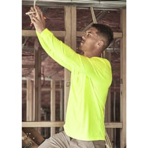 A man wearing a high visibility long sleeve tee in fluorescent yellow, working on electrical wiring in a construction setting.