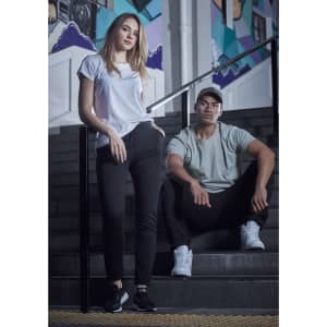A woman in a white T-shirt and a man in a grey T-shirt sit on black stairs, both wearing casual athletic attire.