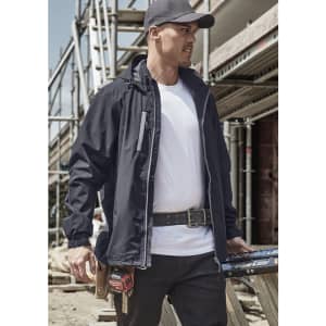 A man in a black packable rain jacket stands at a construction site, wearing a cap and tool belt.