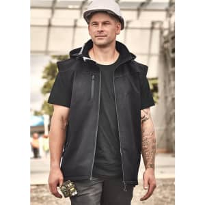 A unisex black softshell jacket features a hood, zippered pockets, and a branding logo, worn by a man at a construction site.