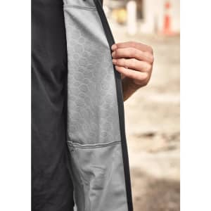 A unisex softshell jacket in black and grey, featuring a textured interior and a hand holding the inner layer.