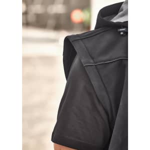 A close-up of a black unisex softshell jacket, highlighting the shoulder and sleeve design. It features a logo.
