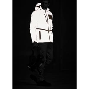 A reflective waterproof jacket in white, featuring a hood, zip pockets, and a logo, displayed on a model in a dark setting.