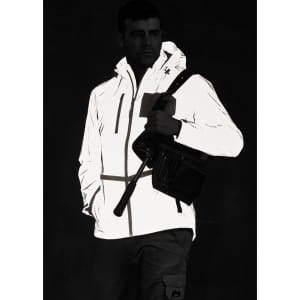 A reflective waterproof jacket in white, featuring a hood and pockets, worn by a model holding a bag.