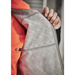 A close-up of an orange unisex softshell jacket showcasing a grey interior with a honeycomb texture and a zipper.