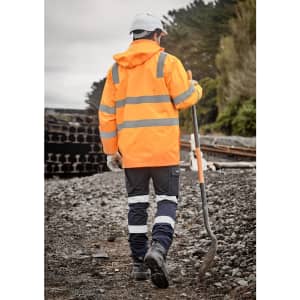 A high visibility orange and navy waterproof jacket with reflective stripes, worn by a person holding a shovel.
