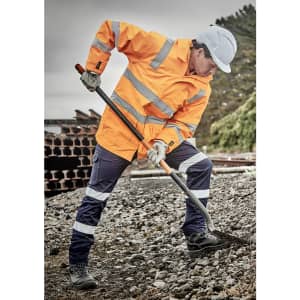 A waterproof orange jacket with reflective stripes, worn by a person digging with a spade, set in an outdoor work environment.
