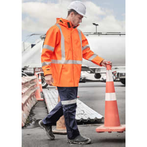 A heavy duty waterproof jacket in bright orange with reflective stripes, worn by a person in a construction environment.