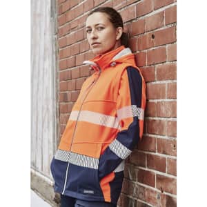 A women's softshell jacket in bright orange and navy, featuring reflective strips and a logo.