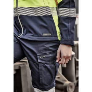 A close-up of a navy and high-visibility yellow softshell work jacket featuring a logo on the left chest and striped detailing.