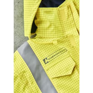 A close-up of a yellow jacket featuring a grid pattern and reflective strips, plus a logo on the front.