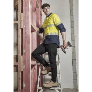 A pair of lightweight black cargo pants worn by a man on a ladder, paired with a yellow and navy shirt and work boots.