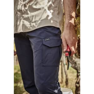 Men's lightweight outdoor cargo pants in navy blue, featuring side pockets and a logo. A hand holds pruning shears.
