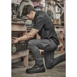 Men's essential basic stretch cargo pants in grey, featuring multiple pockets, worn by a man in a workshop setting.