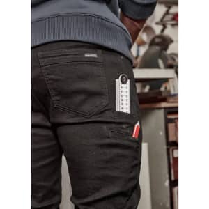 A pair of black stretch jeans with tool pockets and a ruler visible in one pocket, featuring a logo on the back.