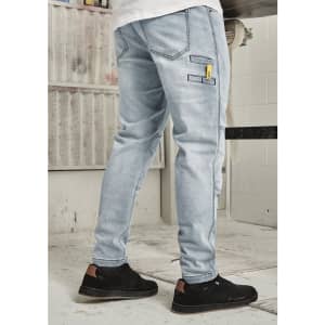 Men’s street-style stretch jeans in light blue, featuring pockets and a logo. Styled with black sneakers.