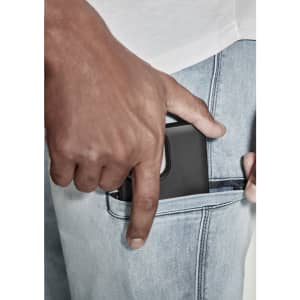 A close-up of a hand placing a phone into the pocket of light blue stretch jeans. The jeans feature a subtle logo.