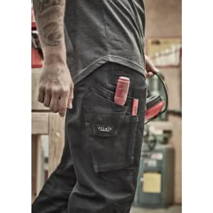 Men's rugged cooling stretch pants in black with multiple pockets and tools visible. The pants feature a logo.