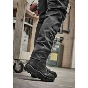 A pair of black rugged cooling stretch pants paired with black boots, set in an industrial environment.