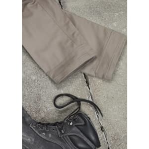 A pair of beige cargo pants laid out flat next to a black boot on a textured surface.