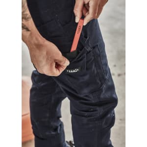 Navy cargo pants with a pocket being used to store a red tool. Features a logo on the pocket.