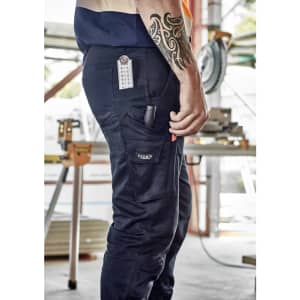 Men's rugged cooling stretch pant in navy, featuring multiple pockets and a logo, displayed in a work environment.