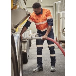 A worker in orange and navy bio motion taped stretch jeans operates equipment in a work environment, featuring reflective strips.