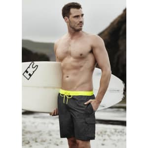 Men's streetwear board shorts in dark grey with a bright yellow drawstring, paired with a surfboard.