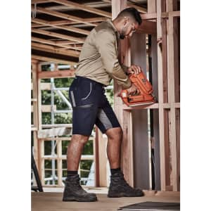 Men's Streetworx Stretch Shorts in navy with grey accents, worn by a man using a nail gun in a construction setting.
