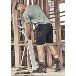 Men's streetwear comfort shorts in black, paired with a green shirt, worn by a man working on a construction site.