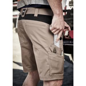 Men's beige work shorts with multiple pockets, featuring a tool in one pocket and a logo on the waistband.
