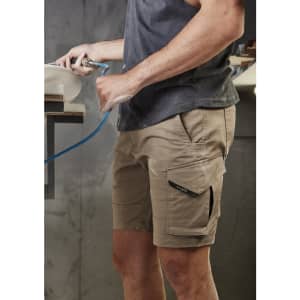 Men's rugged cargo shorts in light brown, featuring multiple pockets and a logo, displayed on a model.