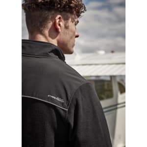 A black unisex quarter-zip polar fleece with a collar and a logo, worn by a model outdoors near an aircraft.