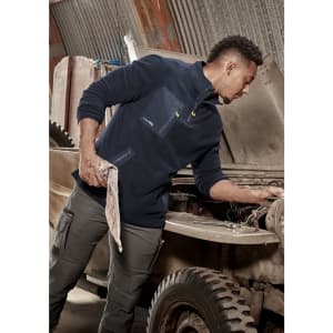 A man in a navy lightweight 1/4 zip polar fleece, working on a vehicle, with a logo on the garment.
