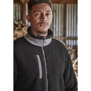 A man models a black full zip Sherpa fleece work jumper with grey detailing and a logo on the chest.