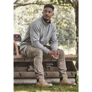 A unisex 1/4 zip brushed fleece pullover in grey, worn with khaki trousers and brown boots, featuring a logo.