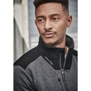 A man wearing a grey and black unisex ½ zip pullover with a reinforced knit design, featuring a logo.