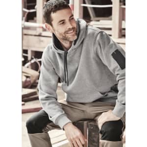 A grey unisex multi-pocket hoodie featuring a logo, worn by a person sitting on a wooden surface.
