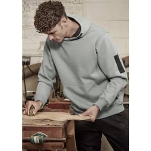 A light blue unisex multi-pocket hoodie worn by a man working in a workshop, featuring a logo on the sleeve.